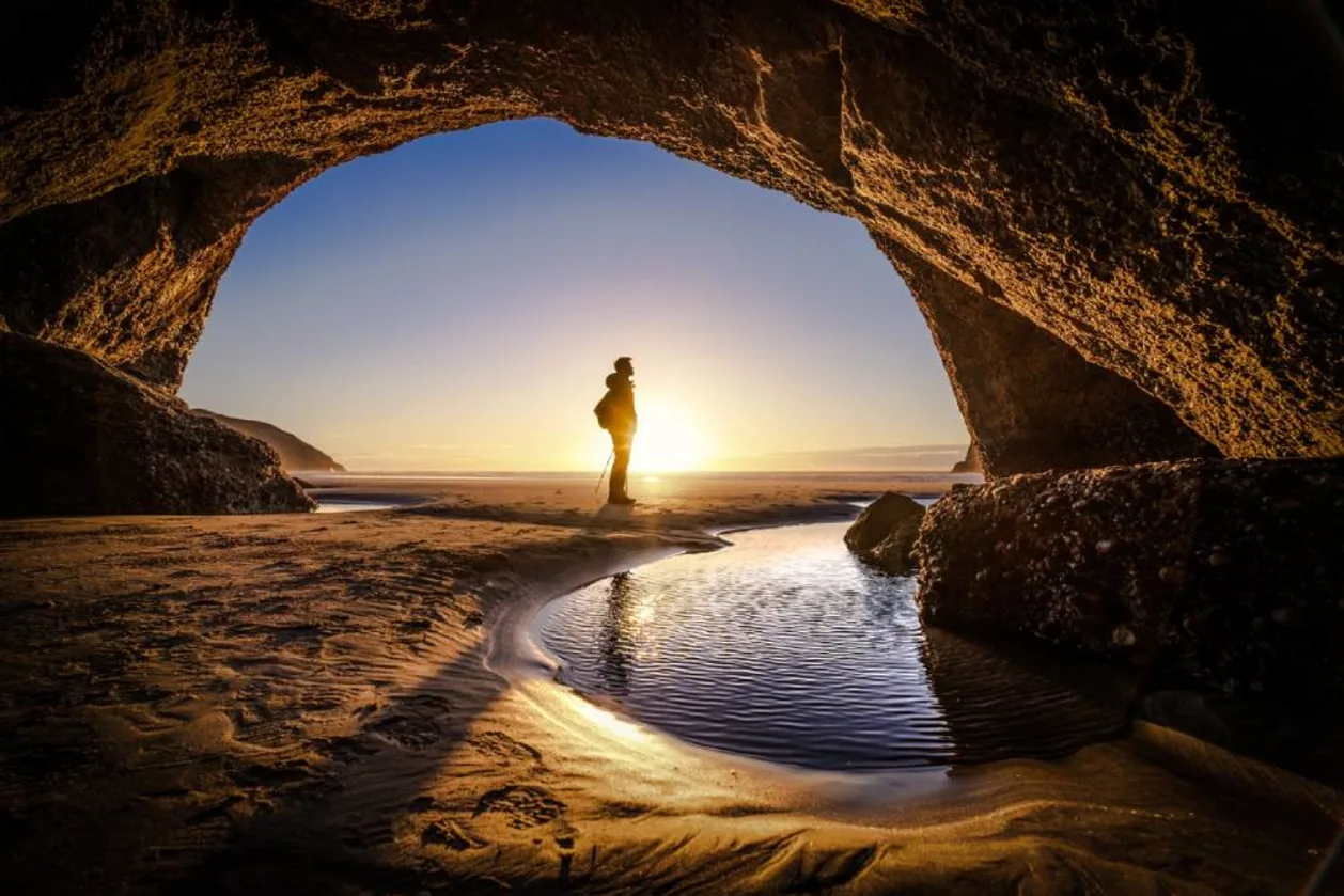 Man stands at cave exit in deep thought in New Zealand